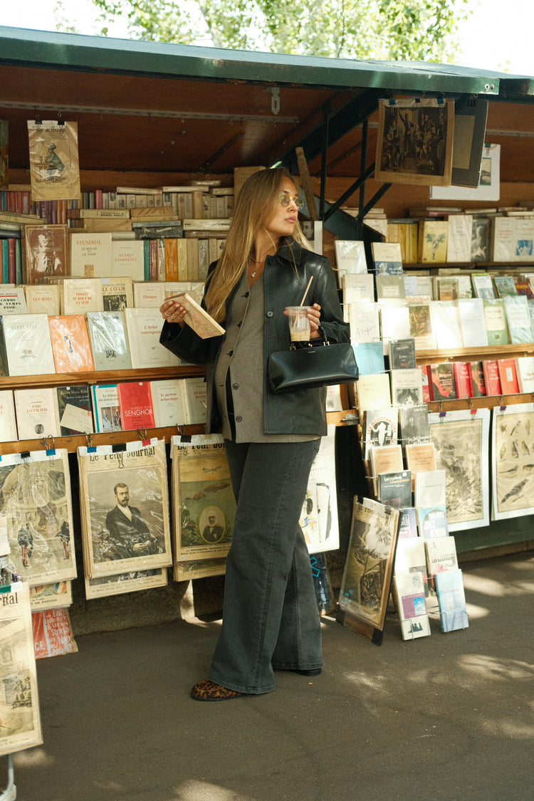Woman in faded black wide-leg maternity jeans at an outdoor bookstall
